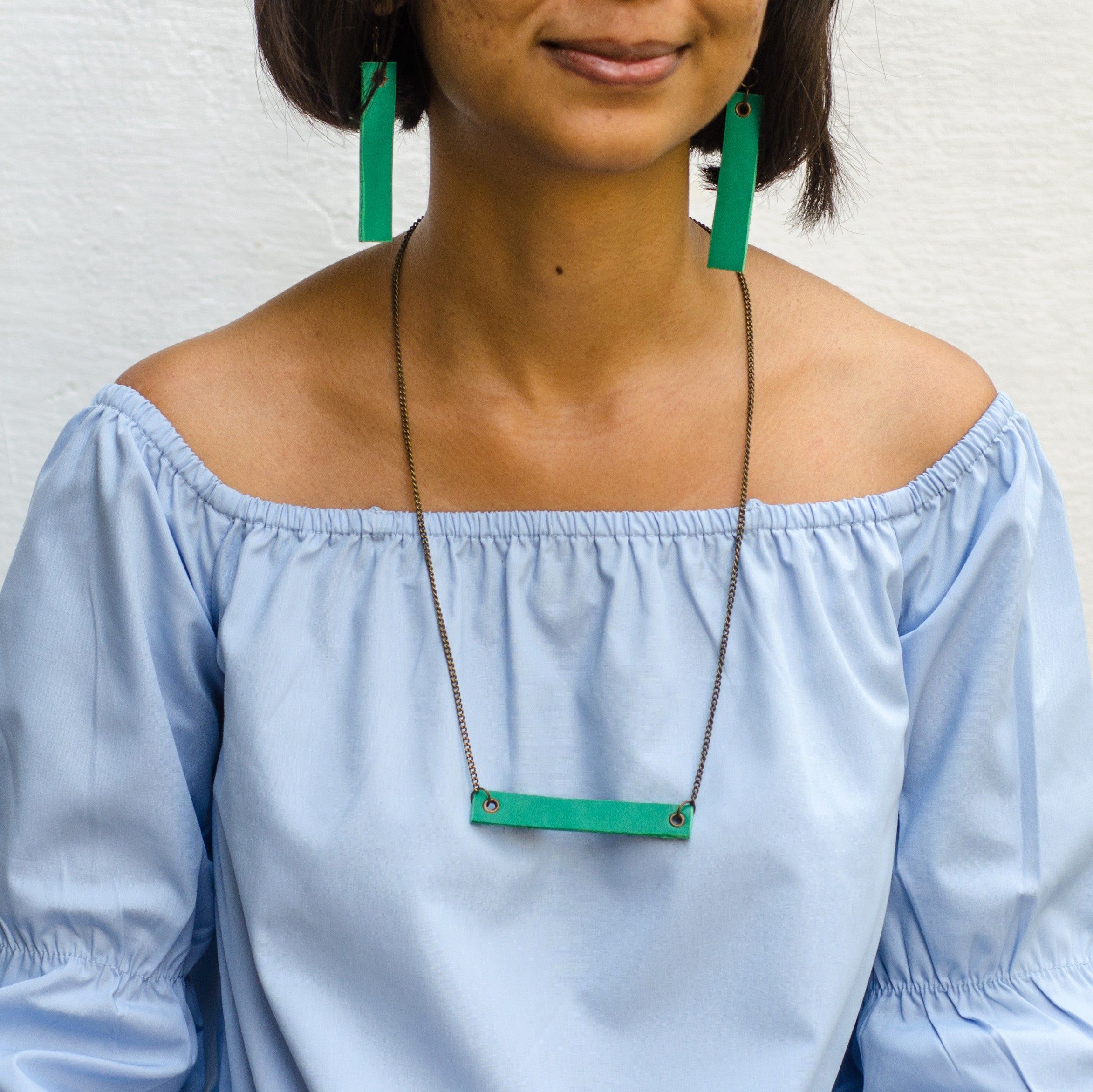 girl wearing leafgreen minimalist rectangular leather earrings and neck piece with antique chain