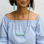 girl wearing mint minimalist rectangular leather earrings and neck piece with antique chain