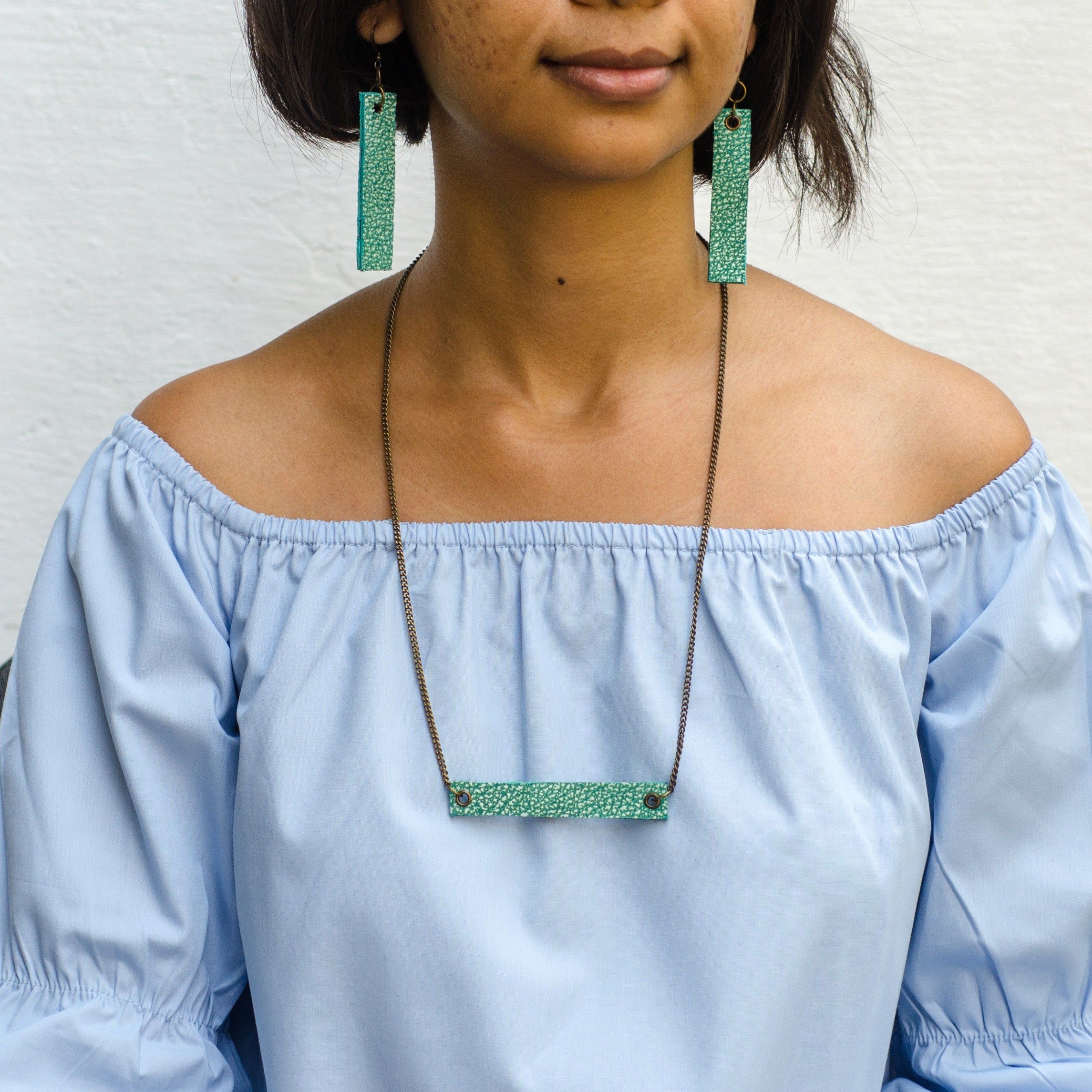 girl wearing seagreen minimalist rectangular leather earrings and neck piece with antique chain