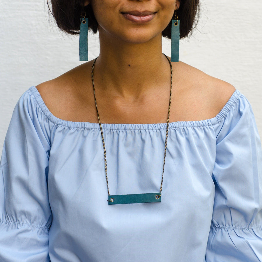 girl wearing torqouise minimalist rectangular leather earrings and neck piece with antique chain